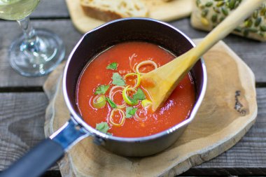 Taze soğan ve otlarla birlikte tencerede ev yapımı domates çorbası..