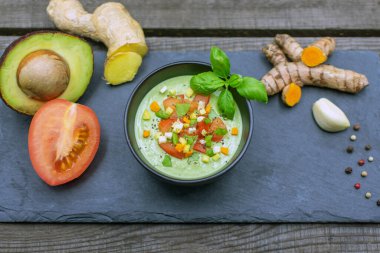 Zencefil, domates ve zerdeçal karışımlı lezzetli avokado kremi siyah bir tabakta servis edilir.. 
