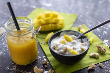Çıtır yoğurt, fındık ve taze mango parçaları. Ezilmiş buzlu mango kokteyli ile servis edilir. 