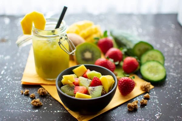 healthy breakfast: crispy muesli with fresh strawberries, kiwi and mango with delicious green smoothie in a jar