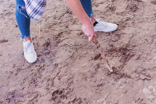 A person draws with a stick in the sand. Location: Germany, North Rhine Westphalia
