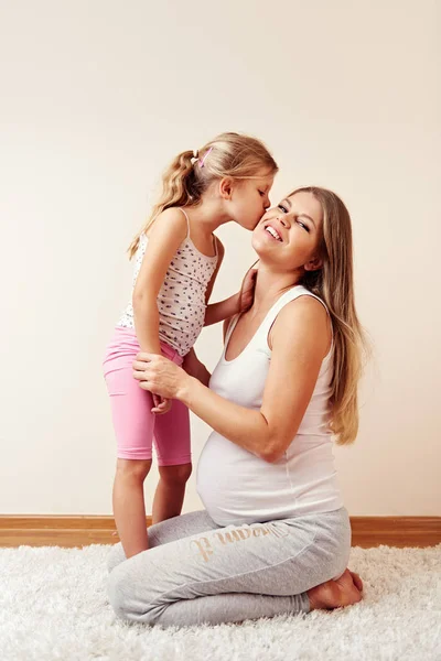 Cute Little Daughter Kissing Her Mother Expecting Baby — Stock Photo, Image