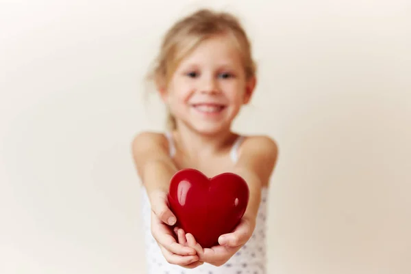美丽的微笑的女孩给红色心脏作为爱和幸福的象征 图库图片