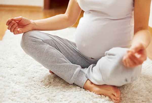 孕妇瑜伽姿势在地毯上的特写 图库图片