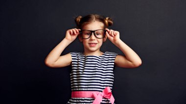 Sevimli kız optik gözlük siyah arka plan üzerine koyarak. Vizyon düzeltme ve tedavi kavramı.