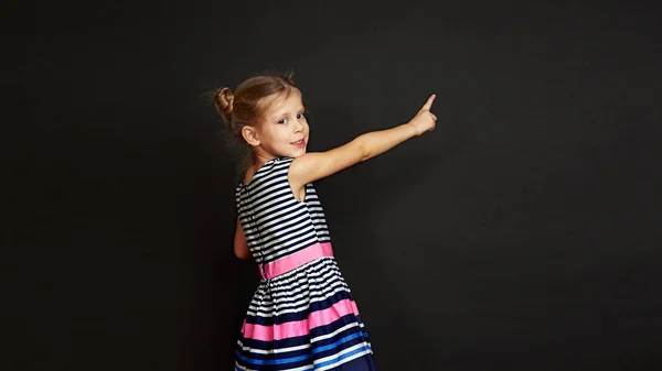 Nettes Schulmädchen Steht Der Tafel Und Zeigt Auf Kopierraum — Stockfoto