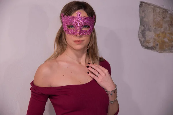 Menina loira com máscara de carnaval fúcsia sobre fundo branco. Mascarada — Fotografia de Stock