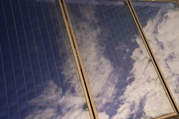 Солнечные панели с отражением голубого неба с белыми облаками — стоковое фото