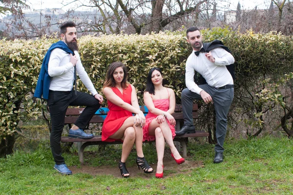 couple of young lovers, two women sitting on a wooden bench, two men in a sporty attitude