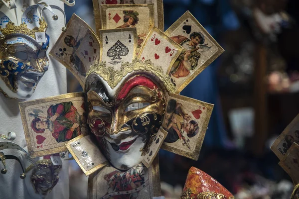 A large joker mask with playing cards. Colored on white with red, black and gold colors. Carnival joke concept. Venetian carnival handmade product in Italy.