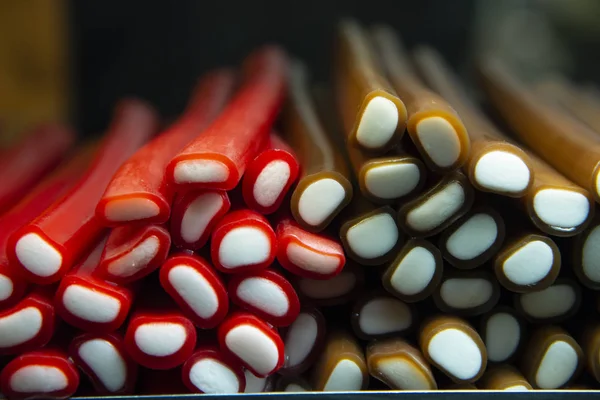 Sweets for sale on a counter at the market. Licorice bars coated in red or brown.