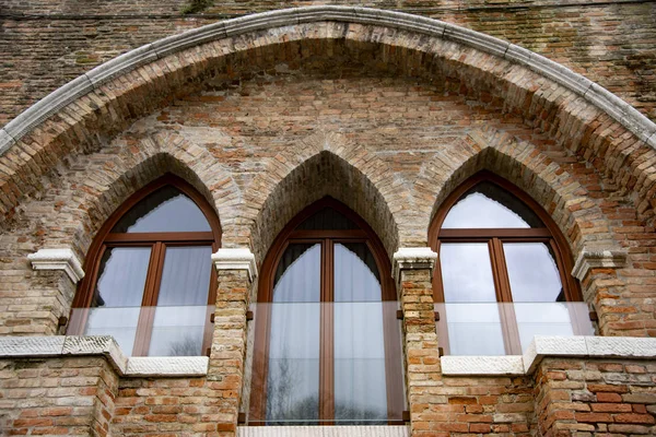 Modern Venetian-style houses with three-light Gothic windows. Brick wall characteristic of the houses of Venice, Italy.