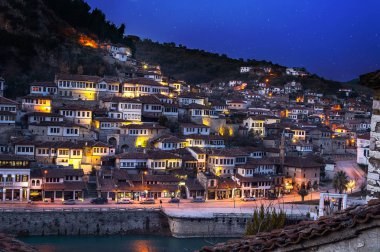 Berat görünümüne akşam, tarihi şehir Arnavutluk Güney ile tüm gece yanıp sönen ve beyaz evler bir tepe üzerinde toplama ışıklar. Gökyüzü yıldızlarla dolu ile mavi saat sırasında yakalanan.