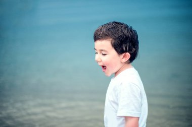 Küçük çocuk zevk plaj zaman beyaz gömlek deniz su turkuaz arka plan 