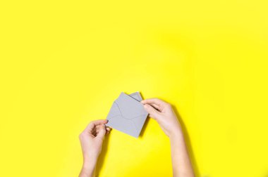 Üstten Görünüm sarı arka plan eller gri zarf açma 