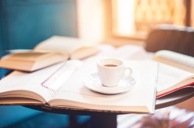 Önden Görünüm fincan espresso açılan kitap güneş ışığı arka planda bir sürü arasında 