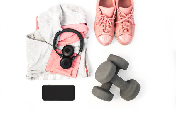 Фитнес и спортивная одежда и аксессуары для женщин на белом фоне: Снейкеры, наушники, мобильный телефон, гантели
