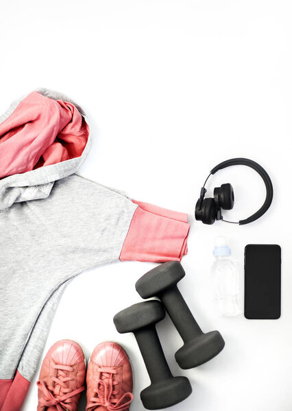 Фитнес и спортивная одежда и аксессуары для женщин на белом фоне: Снейкеры, наушники, мобильный телефон, гантели
