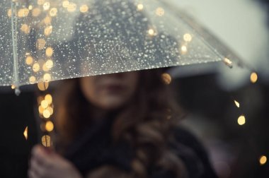 Bulanık şeffaf şemsiye yağmur ile arkasındaki bir kadın yüzü düşer 