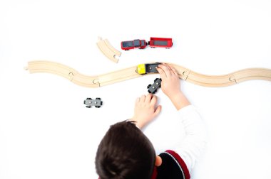 Ahşap demiryolu, trenler ve otomobiller ile oynayan üstten görünüm çocuk