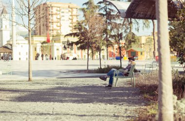 Tiran, Arnavutluk. 4 Mart 2018: ihtiyar ücretsiz hafta sonu vakit insanlara bakmaktan Tiran ana Meydanı, bir bankta oturmuş