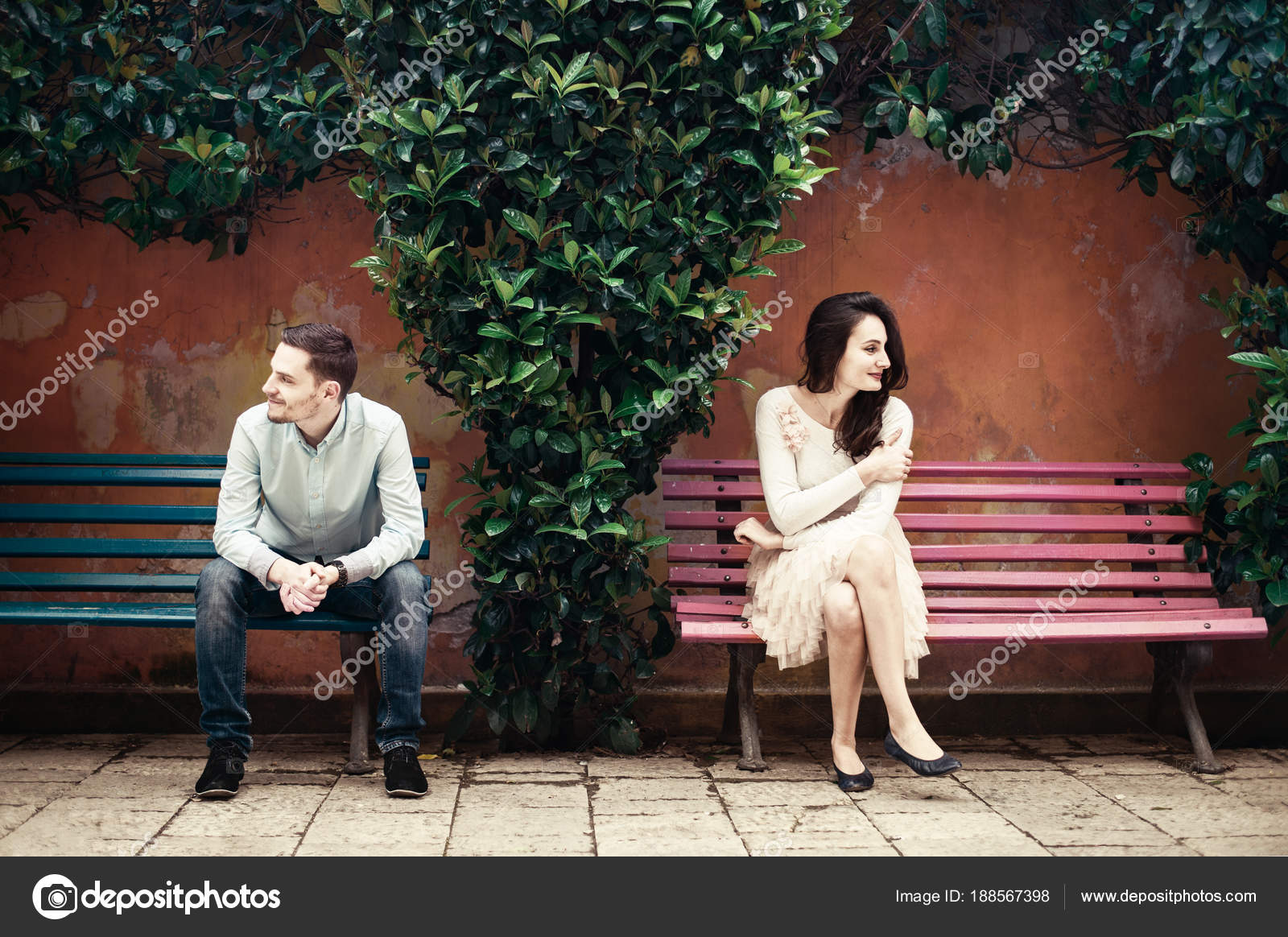Two People Sitting Different Benches Looking Sides Stock Photo
