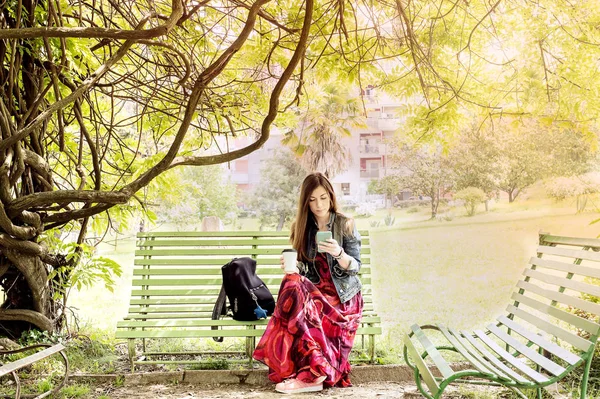 Jeune femme dans le parc assise sur un banc — Photo