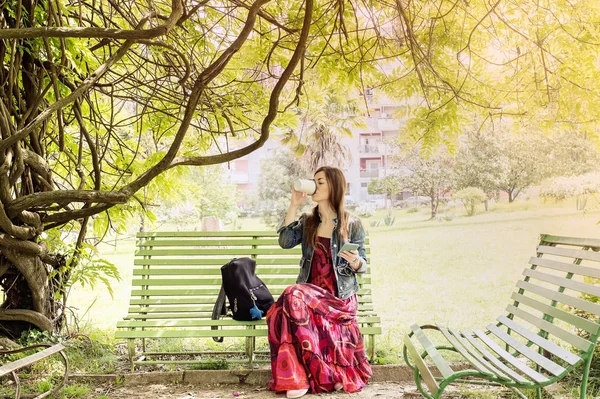 Mujer joven en el parque sentada en un banco — Foto de Stock