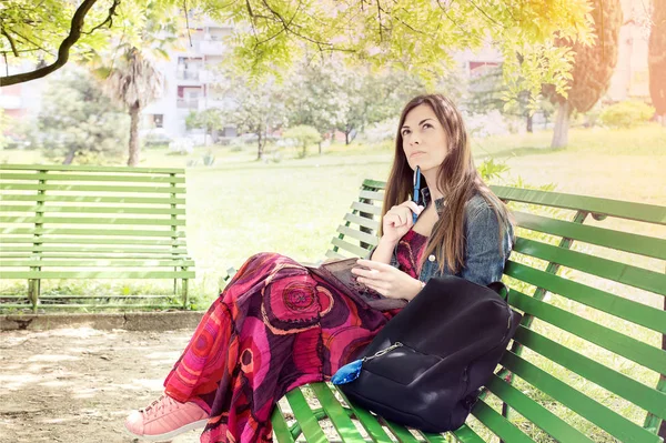 Mujer joven en el parque sentada en un banco — Foto de Stock