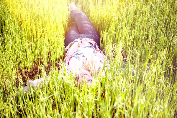 Joven mujer disfrutando de la mentira sobre su espalda en la hierba verde en el jardín . — Foto de Stock