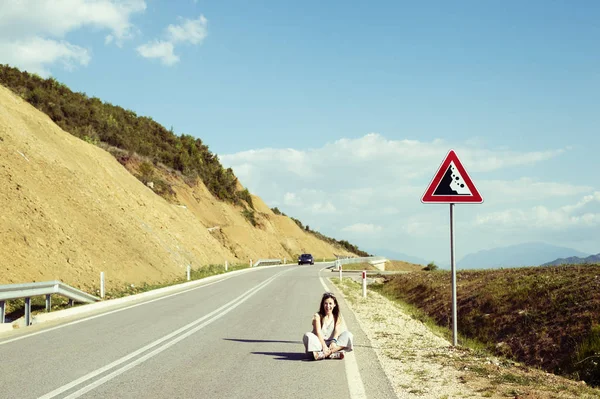 Jovem mulher sentada na estrada — Fotografia de Stock