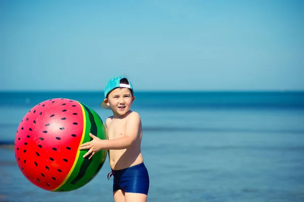 Gelukkig kind gooit zijn gevormd als een watermeloen strandbal — Stockfoto