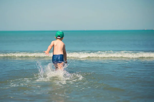 Mały chłopiec biegnie wzdłuż plaży — Zdjęcie stockowe