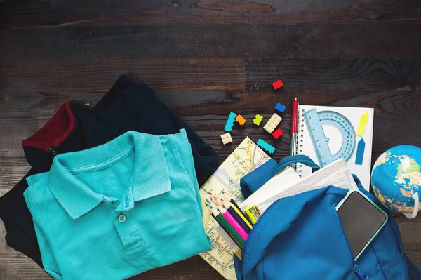 Conceito de educação. Top vista uniforme escolar, crianças, itens em mochila e estacionário em fundo de madeira — Fotografia de Stock