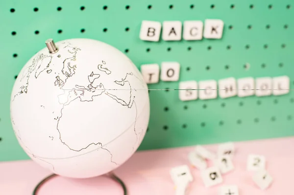 De volta ao material escolar. Globo branco e letras de madeira em uma placa, cores pastel — Fotografia de Stock