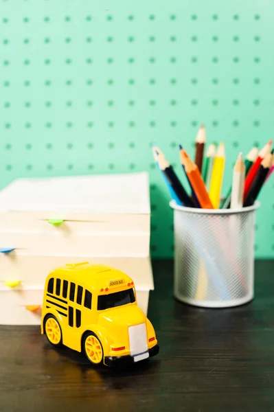 Voltar ao espaço de trabalho material escolar pastel com lápis, livros, ônibus escola de brinquedo — Fotografia de Stock