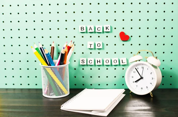 Voltar à escola fornece espaço de trabalho pastel com itens da moda e cartas de madeira em uma placa — Fotografia de Stock