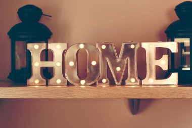 Metal harflerle aydınlatılmış iç dekorasyon fikri ev kelimesini oluşturur