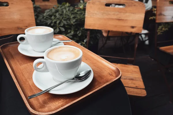 Dua cangkir cappuccino dengan seni latte di latar belakang kayu . — Stok Foto