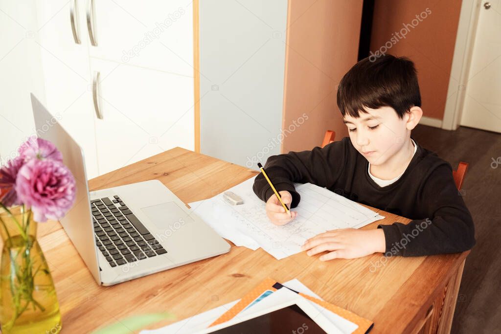 young Caucasian boy following class work online on a laptop computer