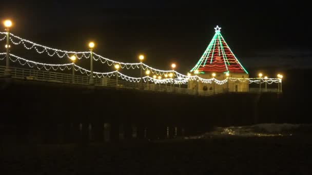 Hermosas Luces Navidad Muelle Reflejándose Las Olas Del Océano Debajo — Vídeos de Stock