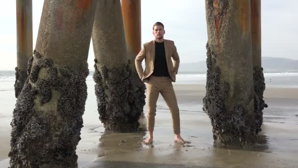 一个穿着西服的英俊年轻人在海滩上的沙滩上 — 图库视频影像