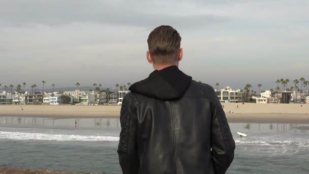 Schöner Junger Mann Der Von Einem Pier Auf Den Strand — Stockvideo