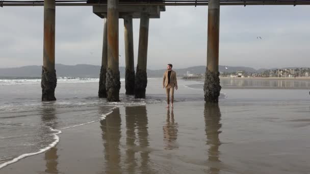 穿着西服的性感男人在海滩上沿着水边散步 — 图库视频影像