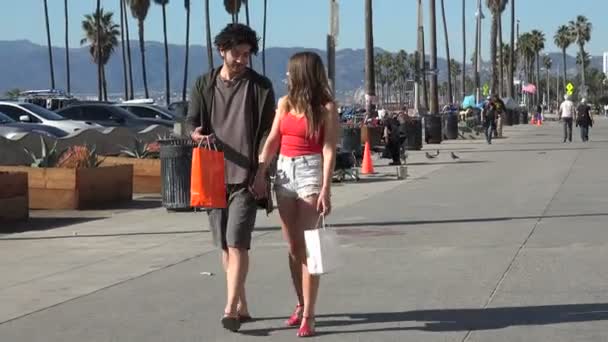 一对浪漫的年轻夫妇在海滩边的木板路上购物 — 图库视频影像