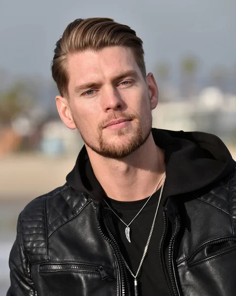 Portrait of a handsome young man in a black leather jacket outdoors