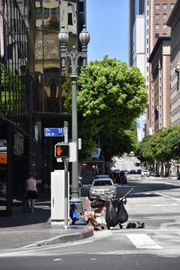Los Angeles, CA / USA - 29 Nisan 2020: COVID-19 karantinası sırasında sokak köşesinde oturan evsiz
