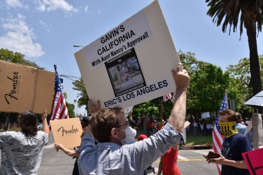 Los Angeles, CA / USA - 8 Mayıs 2020: Anti-Covid-19 karantina protestocusu sokaklardaki evsizlerin görmezden gelinen sağlık sorununa işaret ediyor