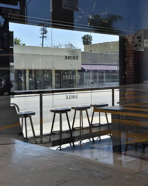 Los Angeles, CA - 9 Mayıs 2020: Terk edilmiş cadde ve kapalı bir restoranın penceresinden Coronavirus karantinası sırasında görülen dükkanlar