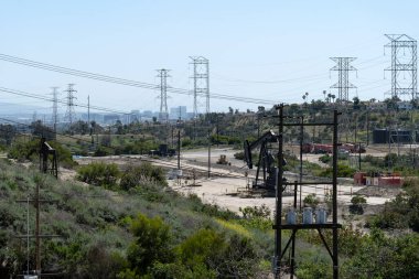 Uzakta Los Angeles silueti olan büyük bir petrol sahası.